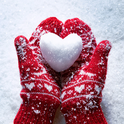 photo of red mittens holding a heart made from snow