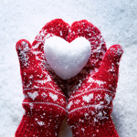 photo of red mittens holding a heart made from snow