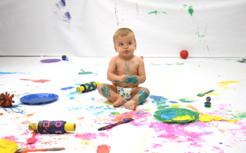 baby surrounded by paint