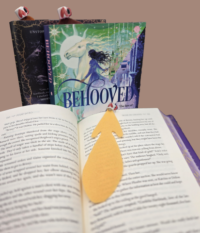 Open book in the foreground with felt book on the open page. Two books upright in the background. All bookmarks have a tiny coffee mug attached.