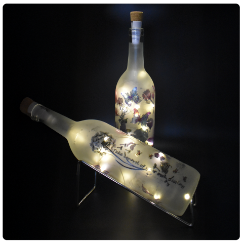 two wine bottles with glowing strings of lights inside