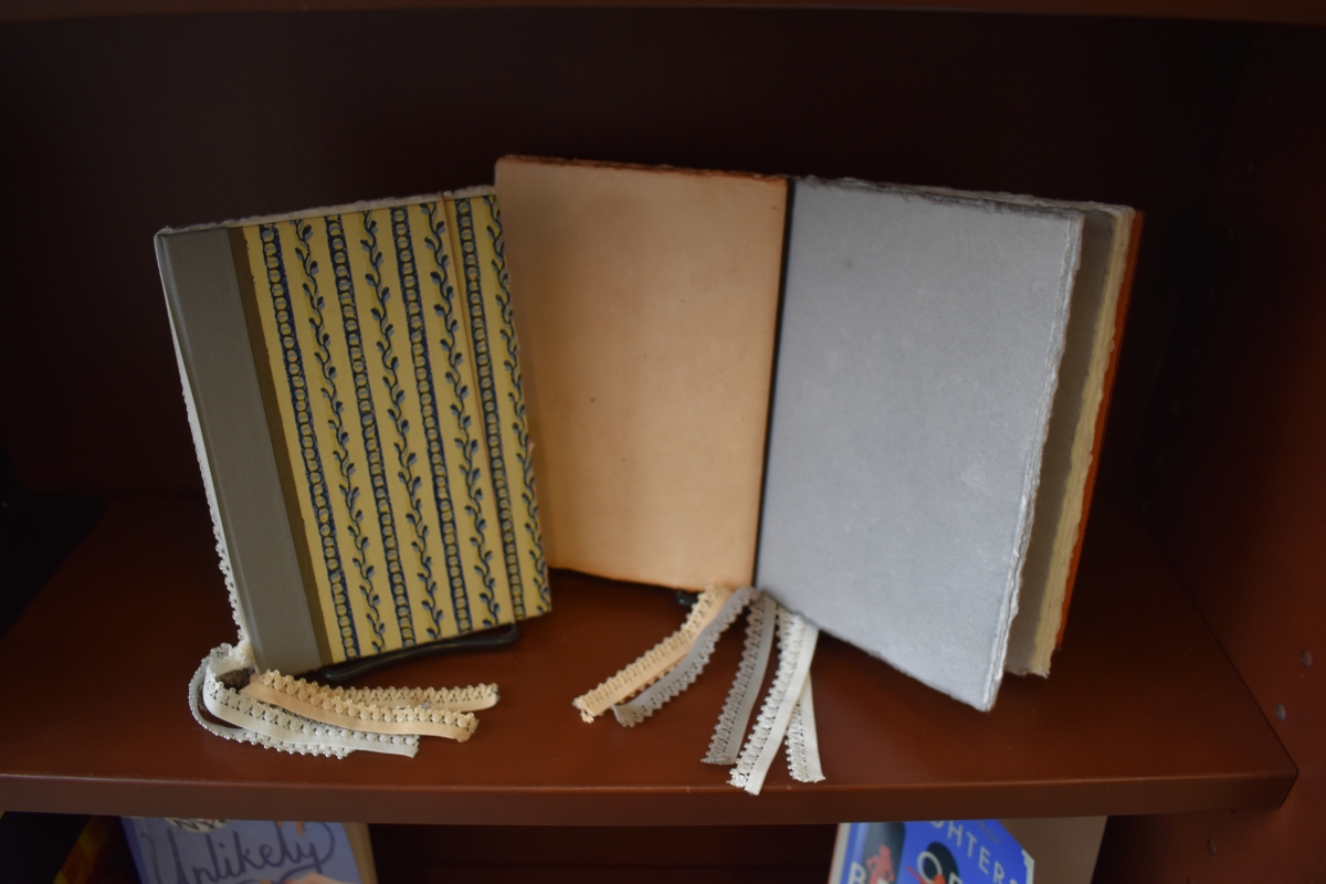 Two hardback notebooks with colored handmade paper and tassels.