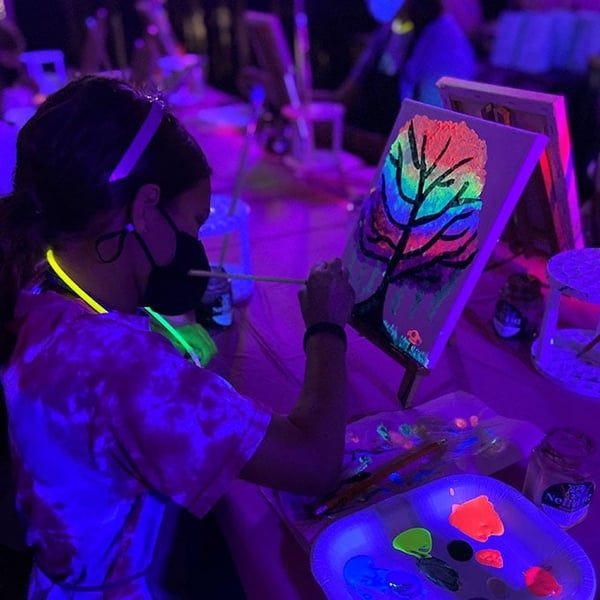 kid painting a tree using glow in the dark paint