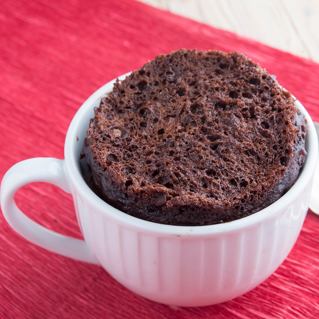 photo of a brownie in a white mug on a red tablecloth